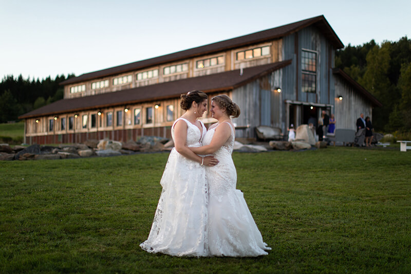 brides posing in front of barn